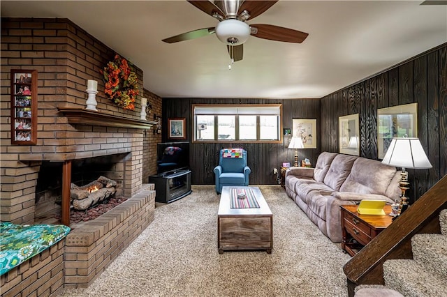 living room with ceiling fan, light colored carpet, wooden walls, and a fireplace