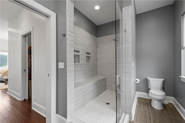 bathroom with a tile shower, hardwood / wood-style flooring, and toilet