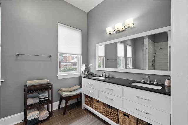 bathroom with wood-type flooring, tiled shower, and vanity