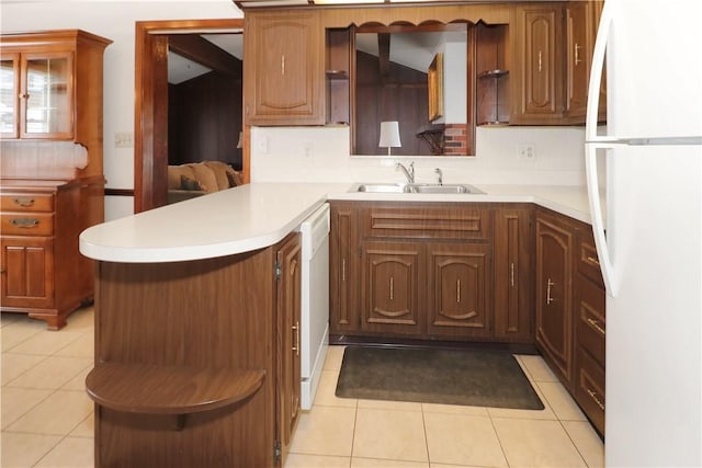 kitchen with light tile patterned floors, kitchen peninsula, decorative backsplash, white appliances, and sink