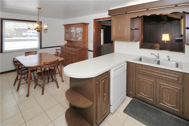 kitchen featuring decorative light fixtures, dishwasher, kitchen peninsula, sink, and an inviting chandelier