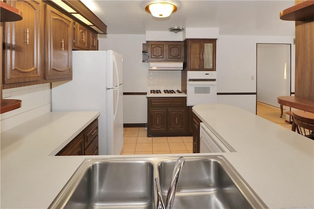 kitchen with light tile patterned floors, extractor fan, tasteful backsplash, white appliances, and sink