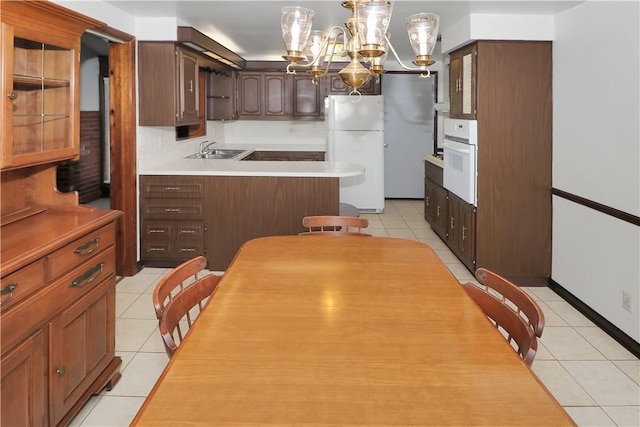 kitchen featuring white appliances, decorative light fixtures, sink, a chandelier, and light tile patterned floors