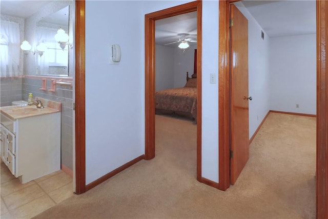 hall with light colored carpet and sink