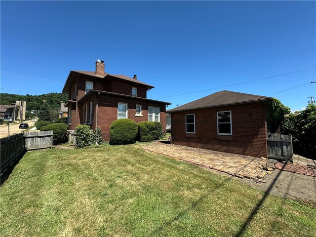 back of property with a lawn and a patio area