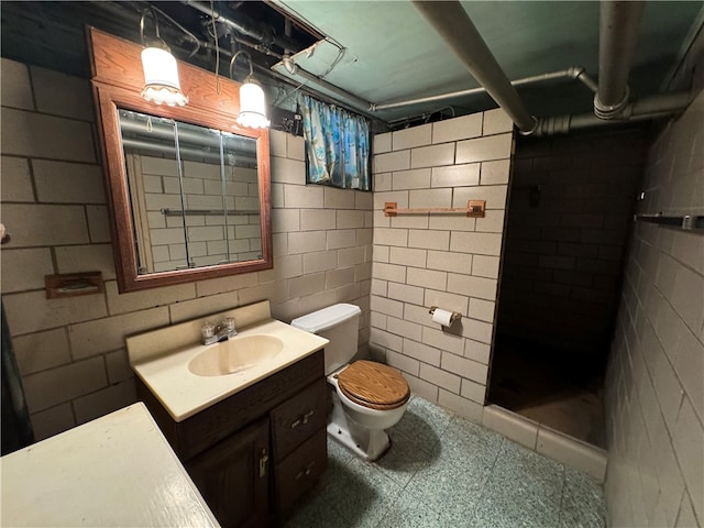 bathroom with tile patterned floors, vanity, tile walls, toilet, and walk in shower