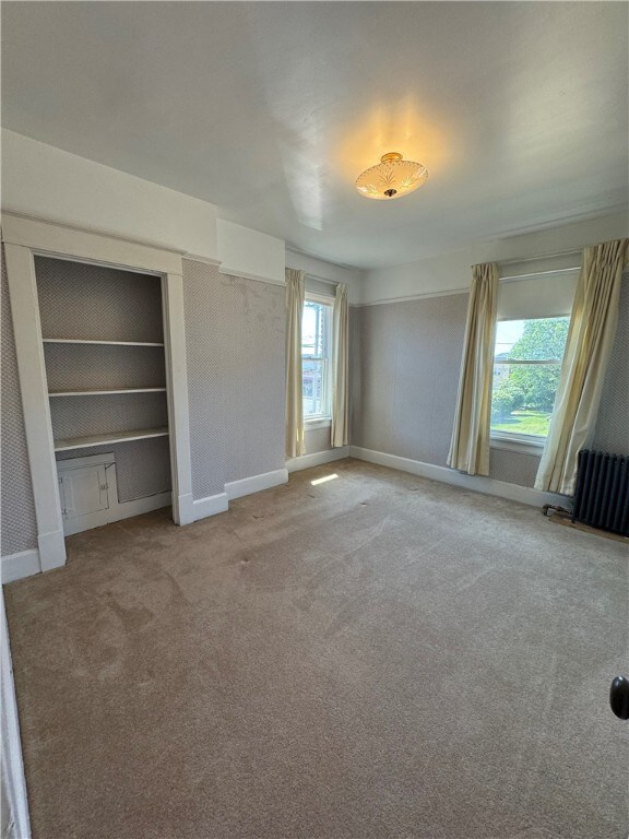 unfurnished bedroom featuring radiator heating unit and light carpet