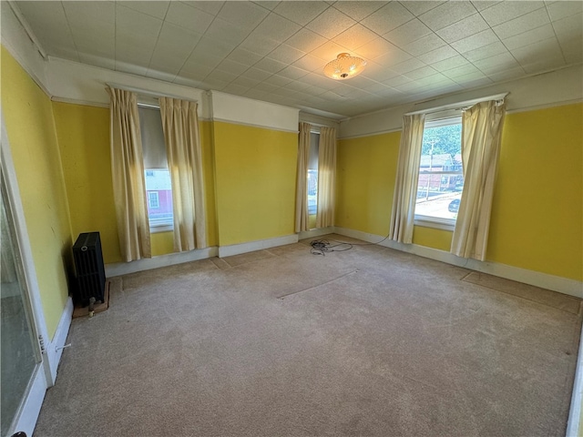 spare room with radiator heating unit and light carpet