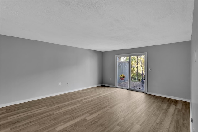 unfurnished room with a textured ceiling and light wood-type flooring