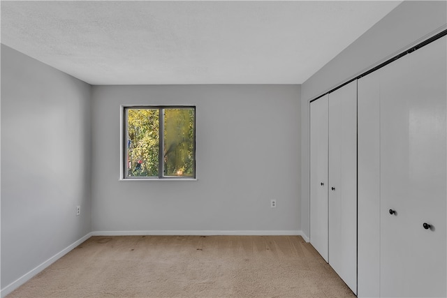 unfurnished bedroom with a textured ceiling, light colored carpet, and a closet