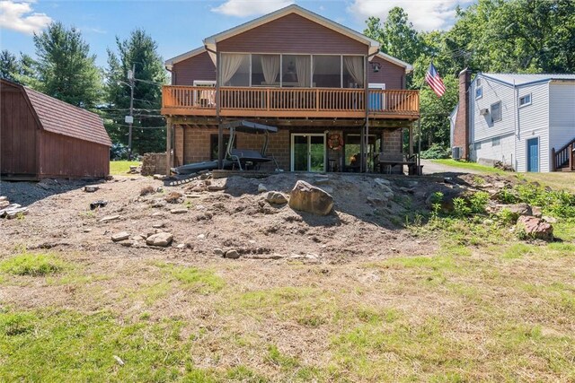 back of property featuring a shed, a sunroom, and a deck