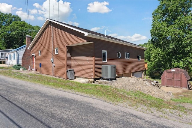 view of side of property featuring central air condition unit, an outdoor structure, and a shed