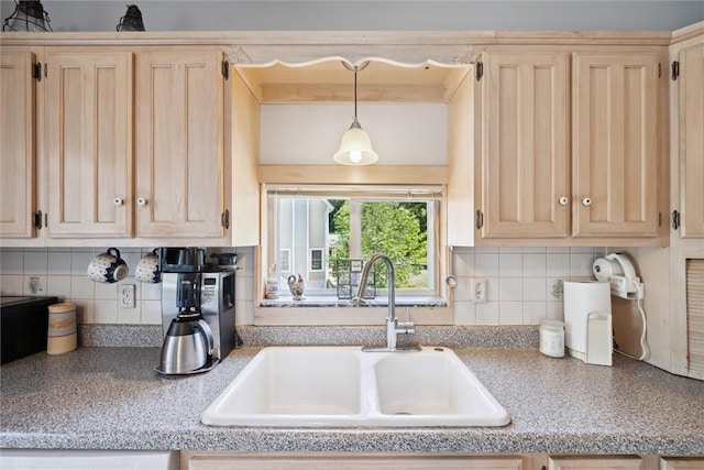 kitchen featuring light brown cabinets, a sink, decorative light fixtures, backsplash, and light countertops