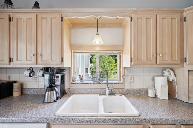kitchen featuring pendant lighting, light brown cabinets, a sink, and decorative backsplash