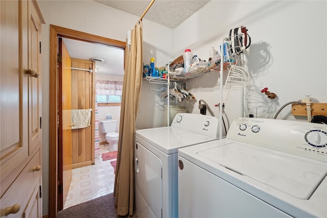 clothes washing area with tile patterned floors, laundry area, washing machine and dryer, and a textured ceiling