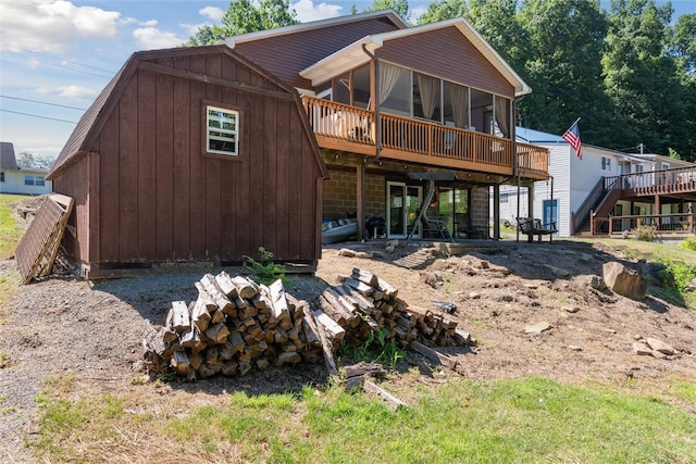 rear view of house featuring stairway, a sunroom, and a wooden deck