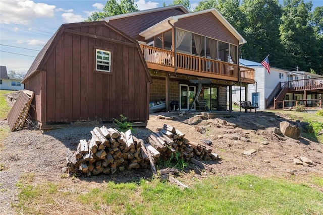 rear view of property featuring a sunroom, a wooden deck, and stairway