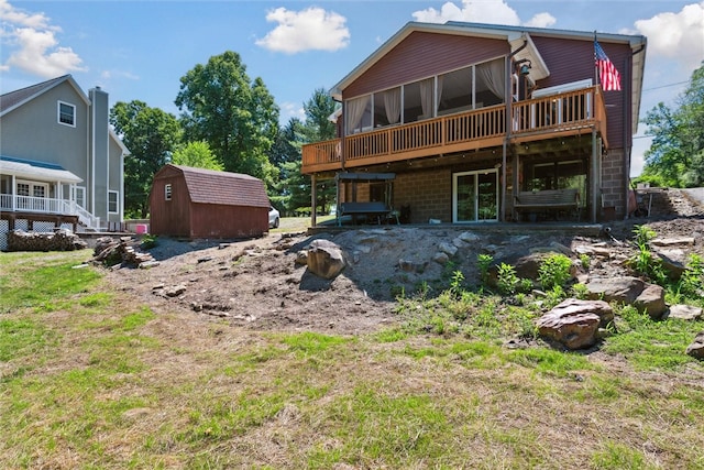 back of house with an outbuilding, a shed, a wooden deck, and a sunroom