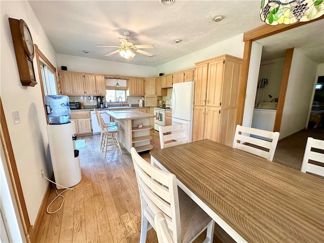 kitchen featuring white appliances, light hardwood / wood-style floors, a kitchen island, and light brown cabinetry