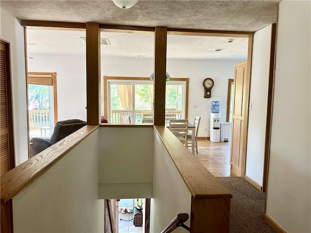 hallway featuring plenty of natural light, an upstairs landing, and baseboards
