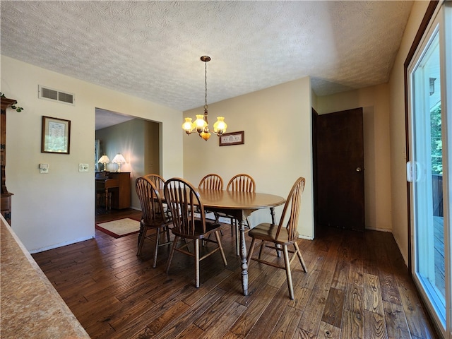 dining space with dark hardwood / wood-style floors, a textured ceiling, and a notable chandelier