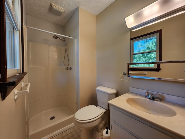 bathroom with a textured ceiling, toilet, a shower, and vanity