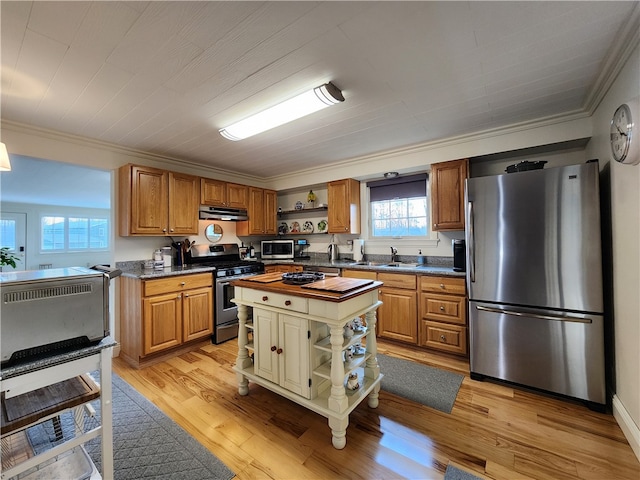 kitchen featuring appliances with stainless steel finishes, light wood-type flooring, a center island, ornamental molding, and range hood