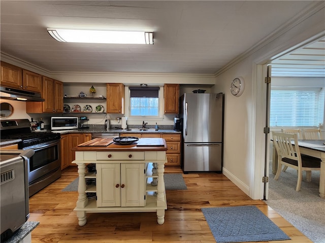 kitchen with ornamental molding, sink, a center island, light hardwood / wood-style floors, and appliances with stainless steel finishes