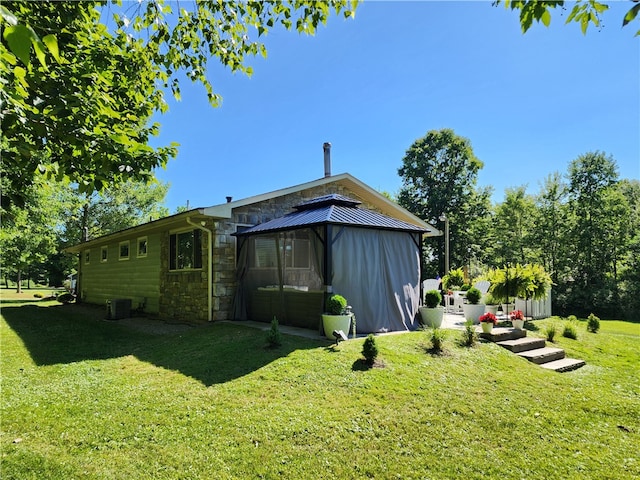 back of property featuring central air condition unit and a lawn