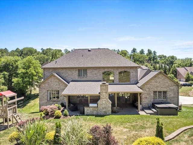 back of property with a yard, a patio, and a hot tub