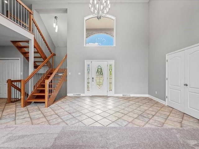 entryway featuring a chandelier, a towering ceiling, and light colored carpet