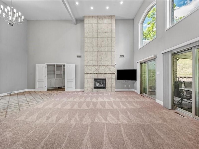 unfurnished living room featuring a healthy amount of sunlight, a towering ceiling, a fireplace, and light carpet