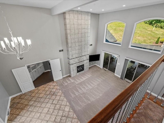 living room featuring beam ceiling, a towering ceiling, an inviting chandelier, and a tiled fireplace