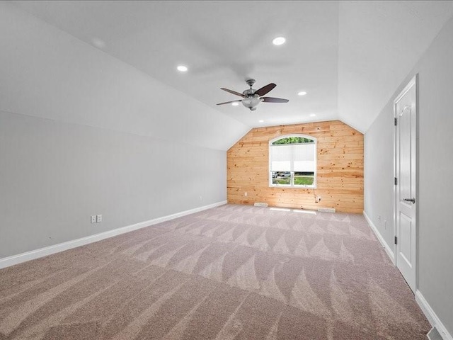 bonus room with wooden walls, ceiling fan, light colored carpet, and vaulted ceiling