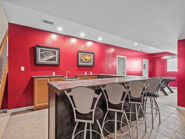 bar featuring a textured ceiling and sink