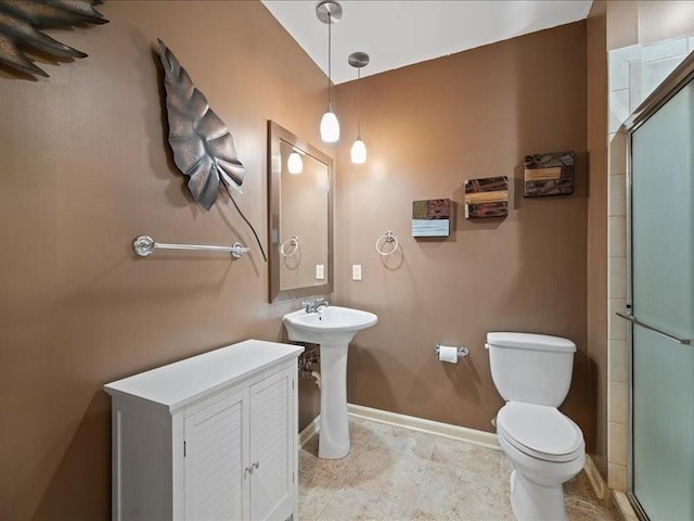 bathroom with sink, a shower with door, and toilet