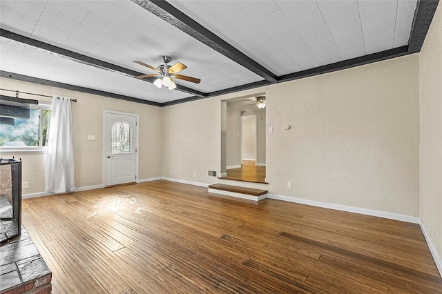 unfurnished living room featuring hardwood / wood-style flooring, ornamental molding, ceiling fan, and beamed ceiling