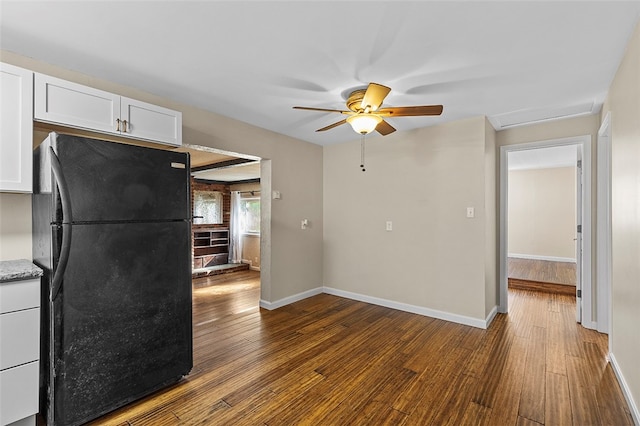 kitchen featuring hardwood / wood-style floors, white cabinetry, black fridge, and ceiling fan