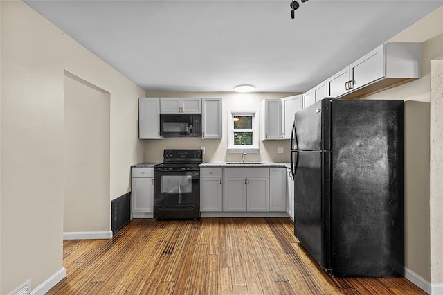 kitchen featuring white cabinets, hardwood / wood-style flooring, black appliances, and sink