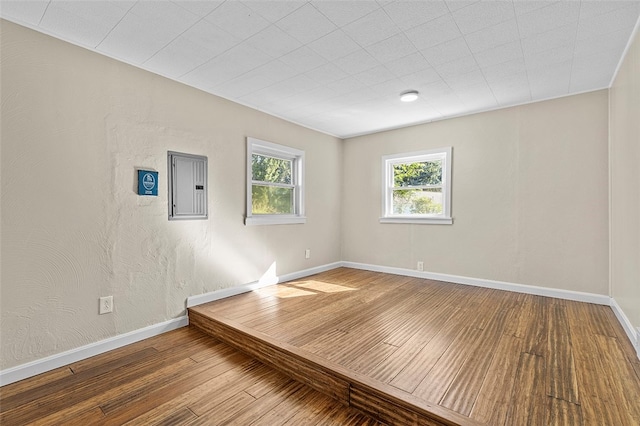 spare room featuring electric panel and hardwood / wood-style flooring