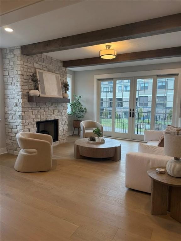 living room with beam ceiling, a fireplace, french doors, and light wood-type flooring