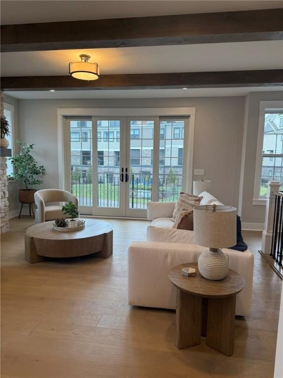 living room with beam ceiling, light hardwood / wood-style flooring, and french doors