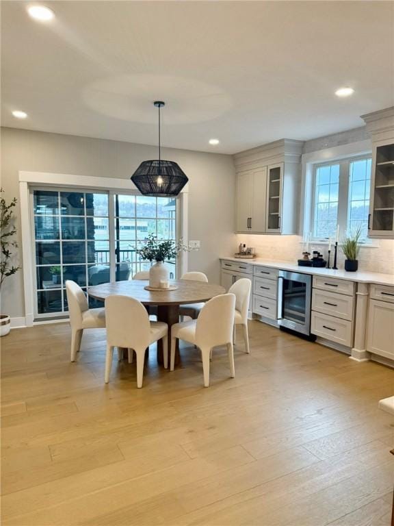 dining room with light hardwood / wood-style flooring, wine cooler, and a wealth of natural light