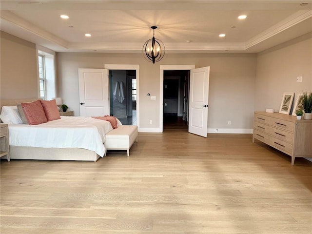 bedroom with a notable chandelier, light hardwood / wood-style floors, and a raised ceiling