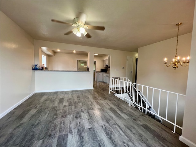 unfurnished living room featuring dark wood-type flooring and ceiling fan with notable chandelier