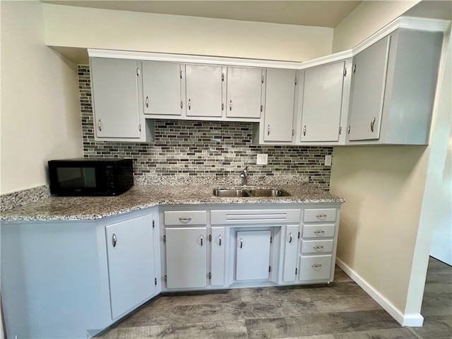 kitchen with gray cabinetry, sink, light stone counters, decorative backsplash, and hardwood / wood-style flooring