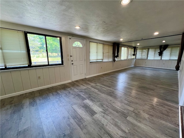 unfurnished living room featuring dark hardwood / wood-style flooring and a textured ceiling