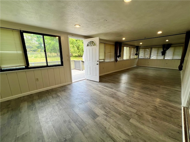 unfurnished living room with dark wood-type flooring and a textured ceiling