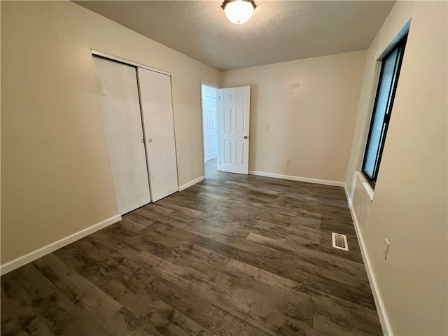 unfurnished bedroom with dark wood-type flooring, a closet, and a textured ceiling