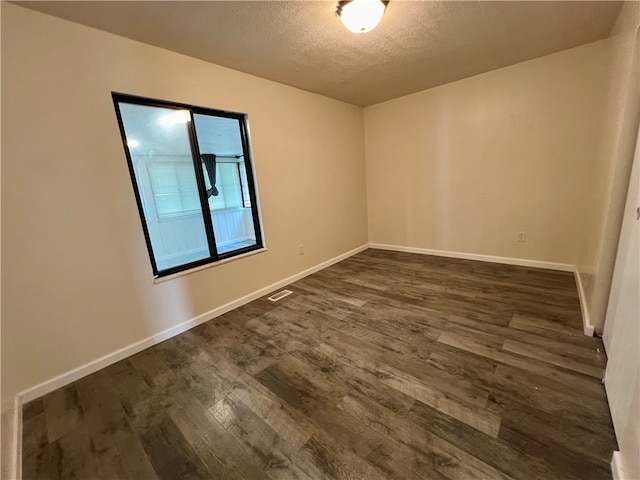 empty room with a textured ceiling and dark hardwood / wood-style flooring